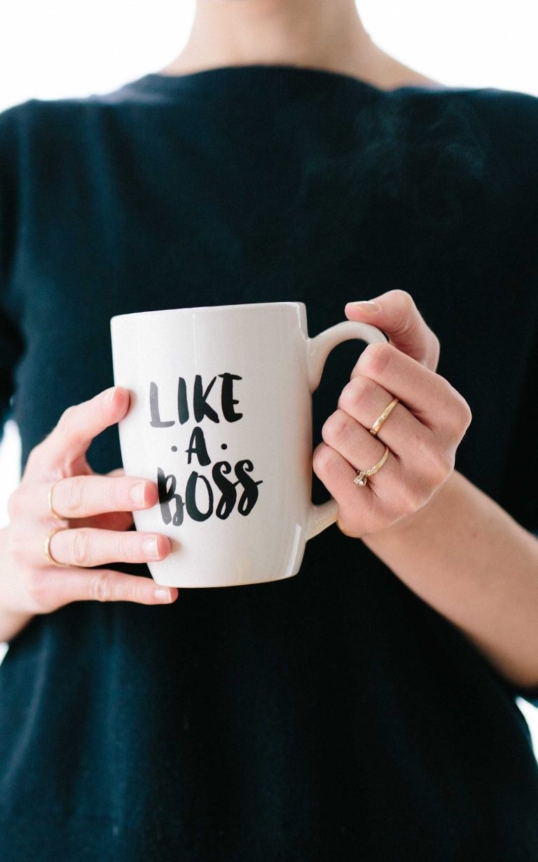 Kaffeetasse mit dem Aufdruck „LIKE A BOSS“ in den Händen einer Person.